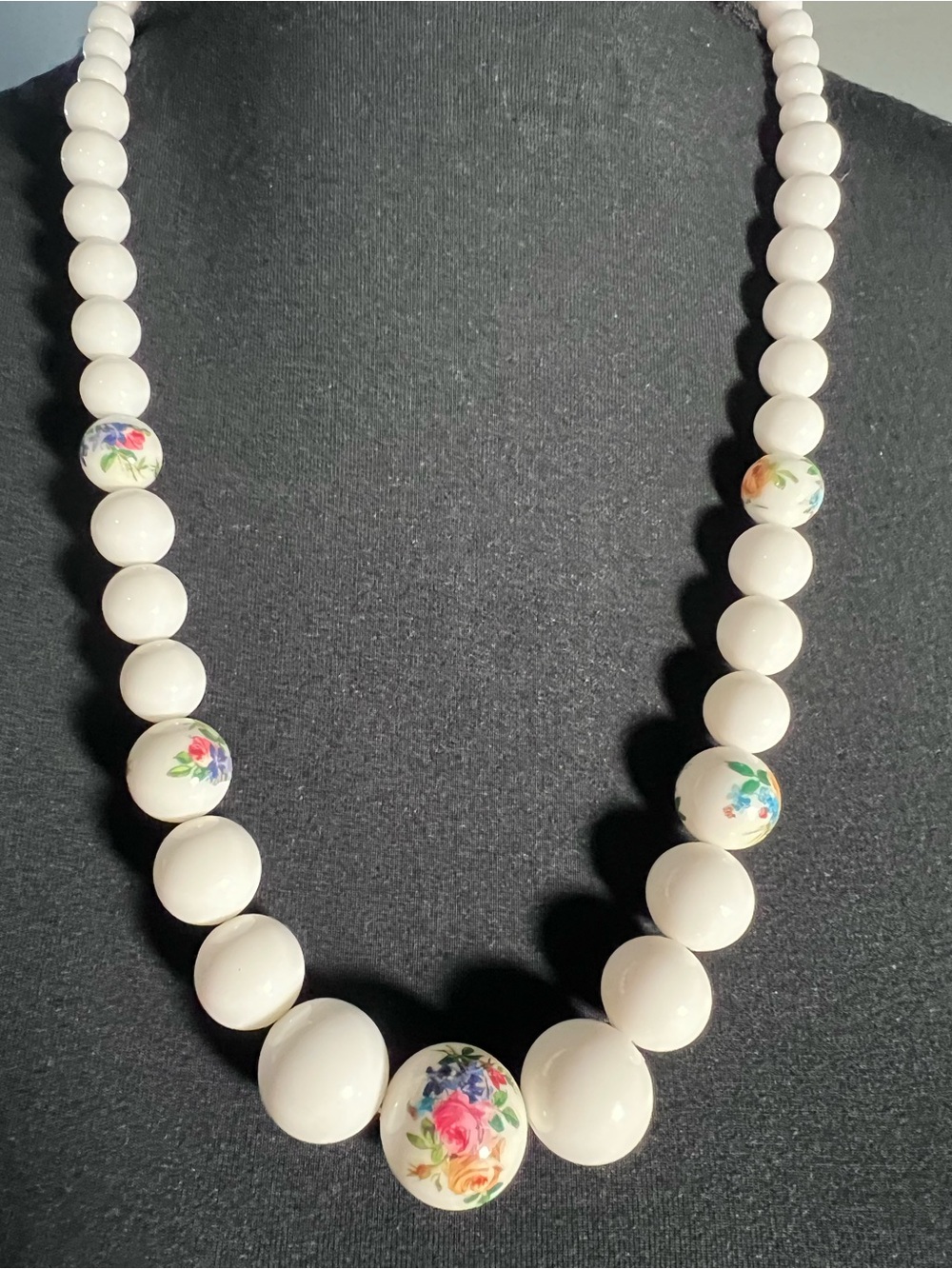 WHITE PAINTED NECKLACE WITH FLORAL DESIGN HAS A BARREL CLASP.